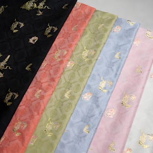 May include: Assortment of patterned fabric in various colors, including black, coral, olive green, light blue, and pink. Each fabric features a repeating gold floral design. The fabrics are arranged diagonally, showcasing their textures and patterns.