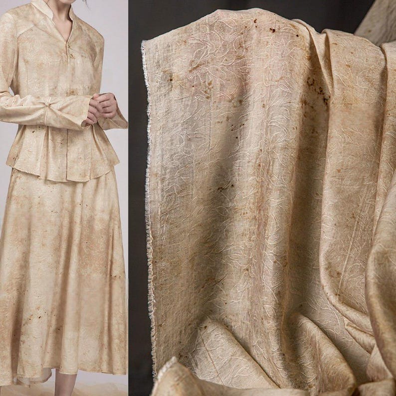 May include: A two-piece beige outfit with a jacket and skirt, alongside a close-up of matching fabric. The fabric has a subtle, organic pattern with brown speckles. The jacket features a peplum design and long sleeves. The skirt is a midi length.