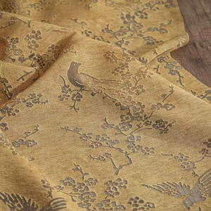 Könnte beinhalten: Eine weiße Keramik-Tasse mit schwarzem Henkel und dem Text "But First, Coffee" in fetter, schwarzer Schrift. Die Tasse steht vor einem verschwommenen Hintergrund, der eine gemütliche Umgebung andeutet.