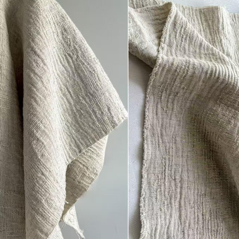 May include: Close-up of a textured, off-white fabric. The fabric has a woven appearance with a slightly crinkled texture. The image shows the edge of the fabric, revealing a raw, unfinished edge. The fabric appears to be a natural fiber, possibly linen or cotton.