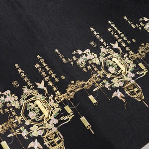 May include: Black fabric with gold floral and lantern designs, and Chinese characters. The design includes flowers, birds, and hanging lanterns. The fabric has a textured appearance.