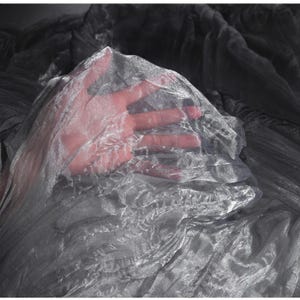 Puede incluir: Primer plano de una tela plateada transparente con textura ondulada. La tela está drapeada, creando pliegues y sombras suaves. La tela es translúcida, permitiendo el paso de la luz. El efecto general es delicado y etéreo.