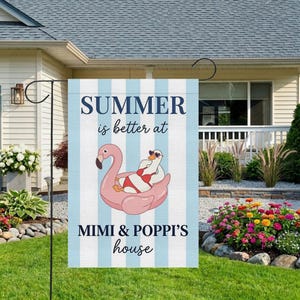 May include: A garden flag with a blue and white striped background. The flag features the text "SUMMER is better at MIMI & POPPI'S house". A flamingo float with a goose wearing sunglasses is in the center.