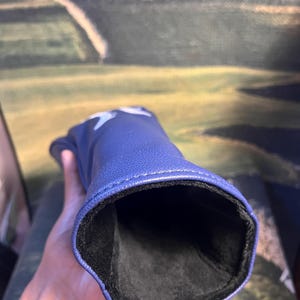 May include: A blue golf club head cover with a star design. The cover is made of a smooth material and has a black interior lining. The cover is designed to protect the golf club head.