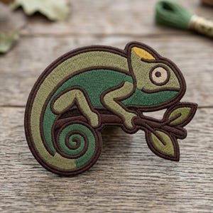 May include: Embroidered patch featuring a green chameleon perched on a brown branch with leaves. The patch has a detailed design with various shades of green and brown, and a yellow accent on the chameleon's head. The patch is designed for sewing or ironing onto fabric.