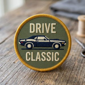 May include: Round embroidered patch with a classic car design. The patch features a navy blue car with white accents on a green background. The words "DRIVE CLASSIC" are embroidered in a cream color. The patch has a gold border.