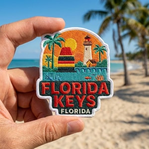 May include: An embroidered patch featuring a tropical scene with a lighthouse, palm trees, and a buoy against an orange sunset. The text reads FLORIDA KEYS FLORIDA in bold red and white lettering on a dark green background with a white border.