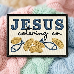 May include: A rectangular embroidered patch with a cream background and a black border. The text reads JESUS in bold blue letters and catering co. in black script. Below the text are two blue fish outlines and five golden yellow bread loaves.