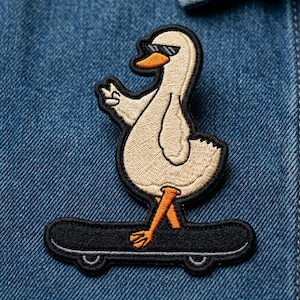 May include: Embroidered patch featuring a cool goose wearing sunglasses and giving a peace sign. The goose is riding a black skateboard with orange feet and beak. The patch has a black border and is on a blue denim background.