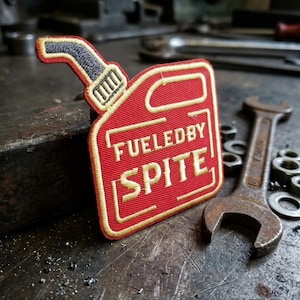 May include: A white ceramic mug with a black handle and the text "But First, Coffee" in a bold, black font. The mug is set against a blurred background, suggesting a cozy setting.