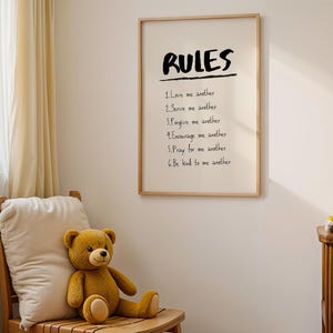 May include: A framed print with the word "RULES" and a list of six rules in black text. A brown teddy bear sits on a wooden chair with a cream-coloured pillow. Additional teddy bears are on a small wooden shelf.