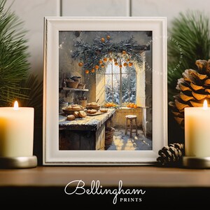 Può includere: Una stampa incorniciata di una scena di cucina con una finestra che si affaccia su un paesaggio innevato. La cucina presenta un tavolo di legno con prodotti da forno, uno sgabello e una ghirlanda di arance. La stampa è circondata da candele accese e pigne.