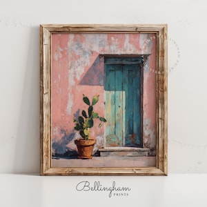 May include: Framed art print depicting a weathered pink wall with a turquoise door and a potted cactus. The artwork has a rustic, painterly style, with visible brushstrokes and a warm color palette. The frame is made of wood.