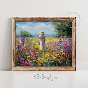 May include: A framed art print showing a person in a white dress and straw hat in a field of colourful wildflowers. The artwork is set against a blue sky and framed in a rustic wooden frame. The print is from Bellingham Prints.