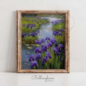 May include: A framed art print featuring a serene landscape of purple irises growing in a pond. The painting has a naturalistic style with visible brushstrokes and a wooden frame. The Bellingham Prints logo is at the bottom.