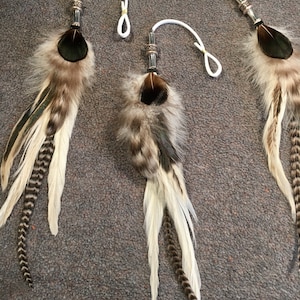 May include: Three feather dreamcatchers with white and brown feathers, black and green accents, and silver beads. The dreamcatchers are hanging from white cords.