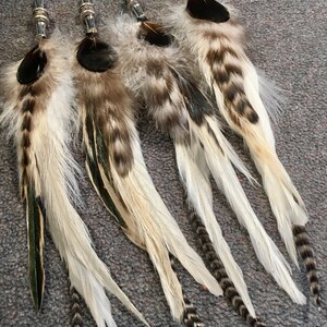 May include: Four white and brown feather hair extensions with silver beads and black tips.