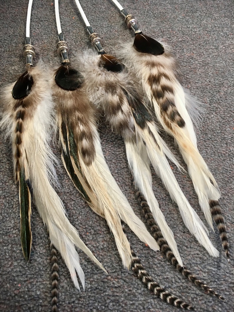May include: Four white and brown feather hair extensions with silver beads and black tips.