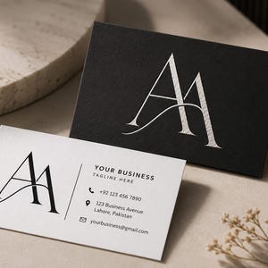May include: Two rectangular business cards featuring a stylized AA monogram. One card is black with a silver embossed monogram, while the other is white with a black monogram and text reading Your Business, Tagline Here, phone number, address, and email.