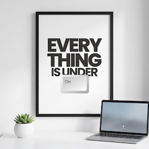 May include: A framed black and white print with the text "EVERYTHING IS UNDER Ctrl" and a computer keyboard key graphic. A laptop and a small potted succulent sit on a white desk.