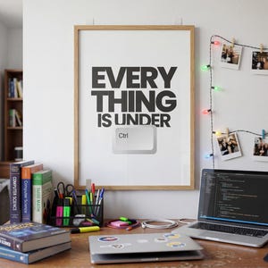 May include: A wooden-framed print displaying the text "EVERYTHING IS UNDER Ctrl" is above a desk with a laptop, books, and stationery. A bookshelf and fairy lights are in the background. The scene evokes a sense of a study or workspace.