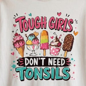 May include: A white t-shirt featuring a colourful graphic of various ice cream treats including a cone, a sundae, a popsicle, and a chocolate bar. The text reads TOUGH GIRLS DON'T NEED TONSILS in pink and teal lettering, surrounded by small hearts and stars.