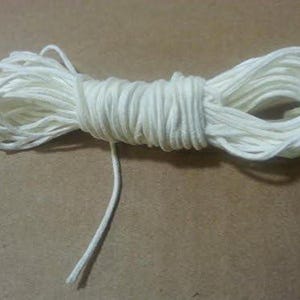 May include: A white cotton cord, wound into a coil, with a long end extending from the coil.