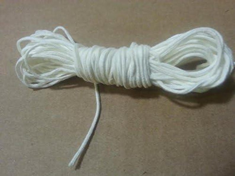 May include: A white cotton cord, wound into a coil, with a long end extending from the coil.