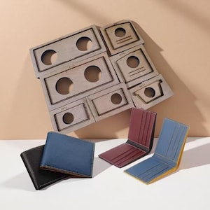 May include: A collection of leather wallets in black, blue, and burgundy, alongside metal die-cut shapes. The wallets are open, showcasing card slots and a contrasting interior. The die-cut shapes have circular and rectangular cutouts.