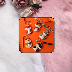 Puede incluir: Cinco llaveros con forma de animal que presentan figuras estilizadas en rojo, naranja, verde, amarillo y negro. Cada llavero incluye una correa de color a juego, una anilla de metal y un pequeño lazo decorativo en la cabeza.