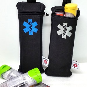 May include: Two black zippered pouches with a medical symbol embroidered on the front. The pouches are labeled "Alert Wear". The pouches are holding two clear epinephrine auto-injectors with green and orange caps.