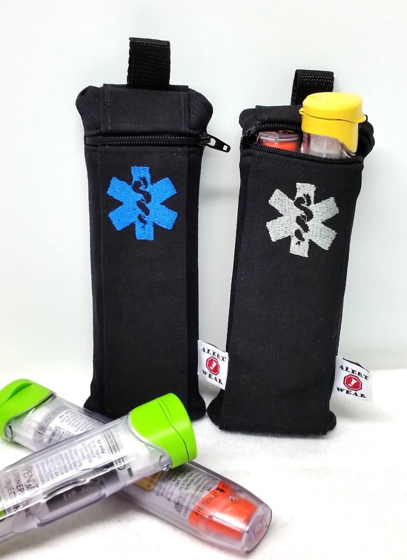 May include: Two black zippered pouches with a medical symbol embroidered on the front. The pouches are labeled "Alert Wear". The pouches are holding two clear epinephrine auto-injectors with green and orange caps.