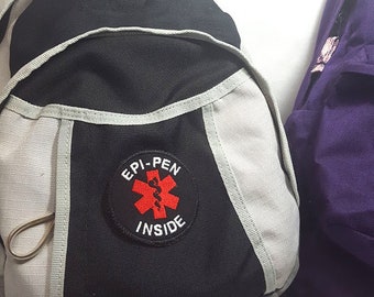 Naszywka na żelazko z ostrzeżeniem medycznym „Epi-Pen Inside” w kolorze czerwono-białym, informująca o alergiach pokarmowych, marki Alert Wear