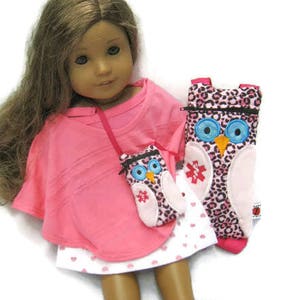 May include: A doll wearing a pink top and a white skirt with pink hearts. The doll has long brown hair and is holding two owl-themed accessories: a small purse and a larger case, both with a pink and black leopard print.