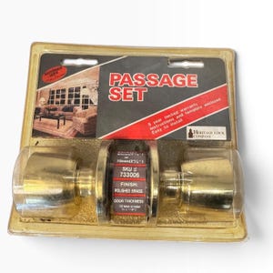 May include: A polished brass passage set door knob in clear plastic packaging. The label reads Passage Set, Heritage Lock Company, SKU 733006, and indicates a backset of 60mm (2 3/8 inches) or 70mm (2 3/4 inches) for door thickness 32mm-51mm (1 1/4-2 inches).