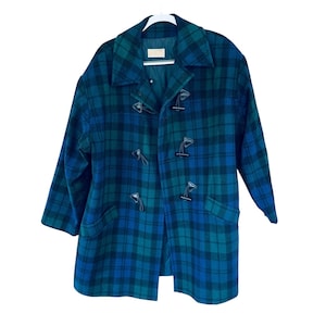 May include: A long-sleeved coat featuring a dark blue and green plaid pattern. The coat has a wide collar, a quilted interior lining, and a front closure consisting of four black toggle fasteners with cord loops. Two side pockets are visible.