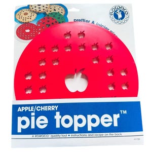 May include: A bright red circular plastic pie topper featuring multiple apple-shaped cutouts of varying sizes. The packaging includes the text APPLE/CHERRY pie topper, the Rowoco logo, and a graphic showing finished pies with the topper in use.