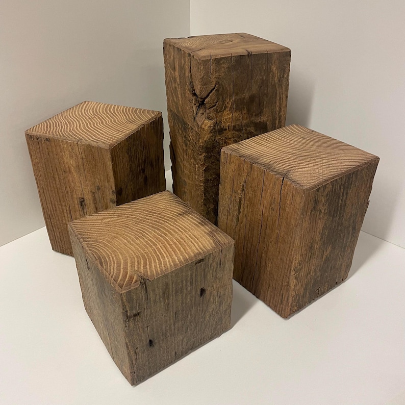May include: A set of four rectangular wooden blocks of varying heights, each featuring a natural brown finish with visible wood grain patterns on the top surfaces and rough, textured sides showing knots and organic wood characteristics.