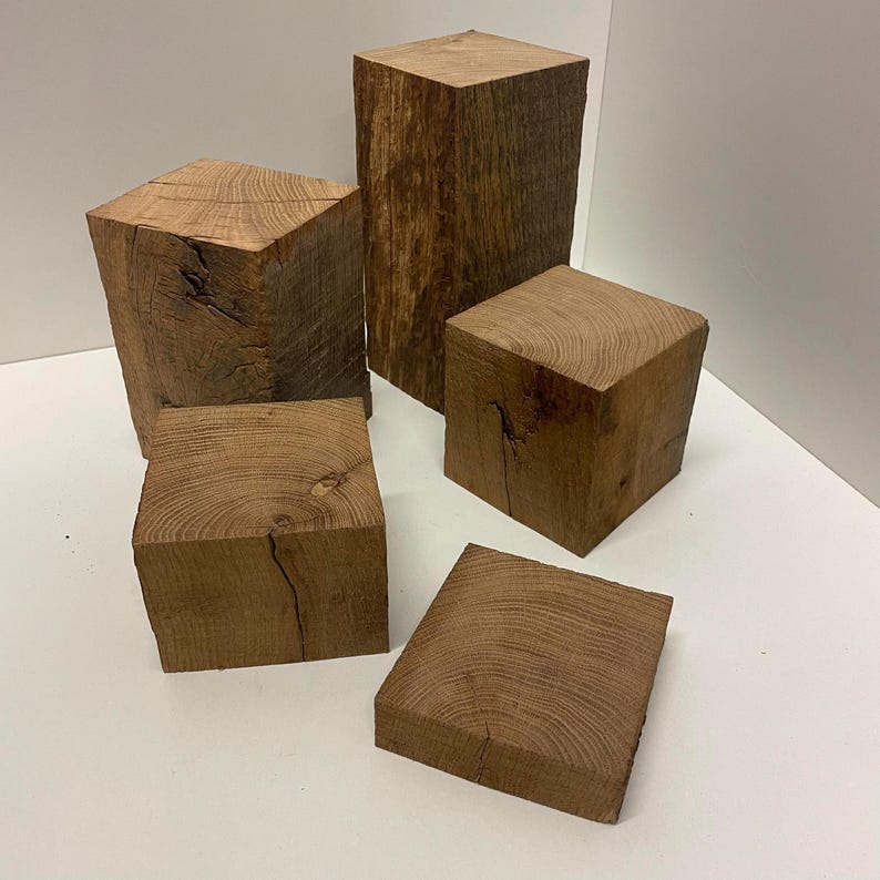 May include: A collection of five natural wood blocks of varying heights and sizes, featuring visible wood grain patterns, knots, and textured surfaces. The blocks are arranged in a group, showcasing the raw, brown, organic appearance of the timber.