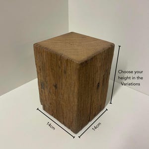 May include: A square wooden block with a natural brown finish and visible grain texture. The block measures 14cm by 14cm at the base, with a vertical dimension that varies. Text on the image reads: Choose your height in the Variations.