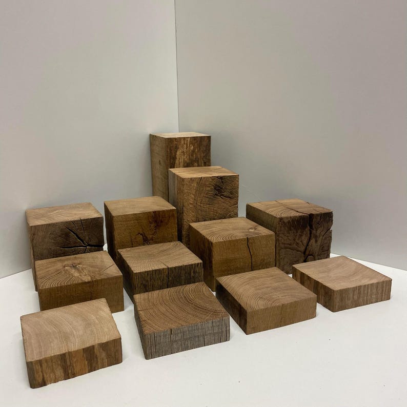 May include: A collection of twelve natural wood blocks of varying heights and widths, each featuring a square or rectangular shape with visible wood grain patterns, knots, and textured surfaces in shades of medium to dark brown.