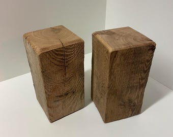 Könnte beinhalten: Zwei rechteckige Blöcke aus natürlichem braunem Holz mit sichtbarer Maserung und texturierten Oberflächen. Jeder Block hat eine flache Oberseite mit kreisförmigen Jahresringen und vertikale Seiten mit rauer Optik.