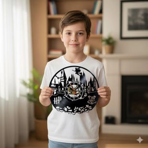 Könnte beinhalten: Eine schwarze Vinyl-Schallplattenuhr mit einer Burgsilhouette und einer Hexe auf einem Besen. Das Zifferblatt ist kreisförmig mit Zeigern. Auf der linken Seite stehen die Buchstaben "HP".