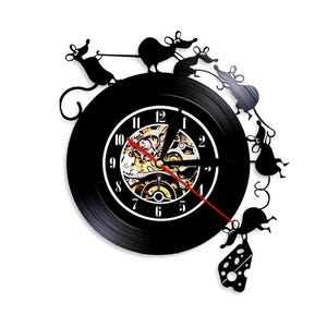 May include: Black wall clock with a unique design featuring silhouette mice climbing on a clock face. The clock hands are red, and the clock face has a visible gear mechanism.