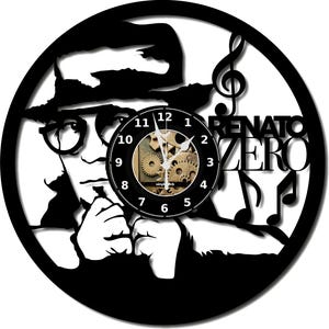 Peut inclure: Horloge murale noire représentant une silhouette d'une personne portant des lunettes et un chapeau. Le cadran de l'horloge est noir avec des engrenages visibles, le texte "Renato Zero" et des notes de musique.