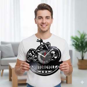 Könnte beinhalten: Eine schwarze Vinyl-Schallplattenuhr mit einem Motorrad-Design. Das Zifferblatt ist in die Motorradfelge integriert. Das Wort "MOTORCYCLE" wird unter dem Zifferblatt mit drei Sternen angezeigt. Die Zeiger sind schwarz und rot.