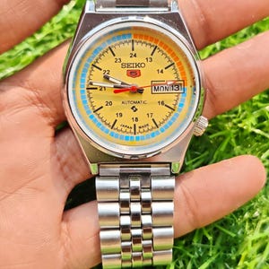 Reloj de pulsera Seiko 5 automático vintage restaurado con esfera amarilla y fecha.