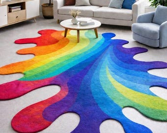 May include: A colorful, abstract rug in a living room setting. The rug features a rainbow design with a splash-like shape, transitioning from red to purple. The rug is placed on a light gray floor, complementing the room's neutral tones.