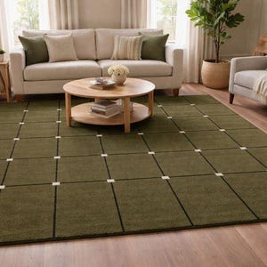 May include: A large rectangular area rug featuring an olive green base color with a grid pattern formed by thin black lines and small white square accents at each intersection, creating a structured geometric design across the entire surface.