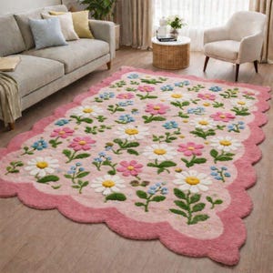 Peut inclure: Tapis rose à bordure festonnée, orné d'un motif de fleurs blanches, roses et bleues avec des tiges et des feuilles vertes. Le tapis est posé sur un parquet dans un salon.